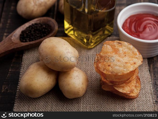 Fresh potatoes and crisps with pepper and sause on wooden board.Potatoes,ketchuo,olive oil.