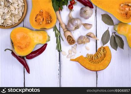 fresh pumpkin and pumpkin seeds on a white wooden background, empty space at the bottom, top view