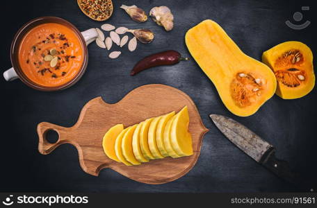 fresh pumpkin chopped and thick soup in a ceramic plate on a black background, top view
