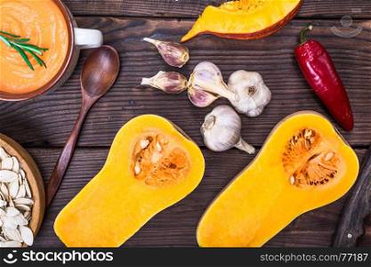 fresh pumpkin cut in half and pumpkin soup in a plate on the table, top view