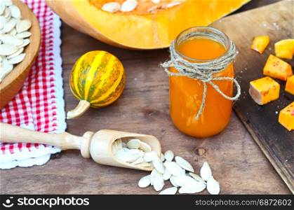 fresh pumpkin juice in a glass jar, next to scattered pumpkin seeds