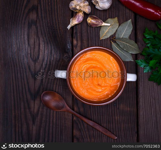 fresh pumpkin soup in a ceramic plate, top view
