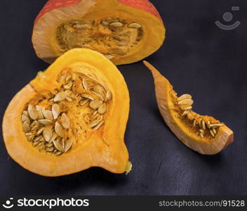 fresh pumpkin with seeds cut in half on a black background, close up