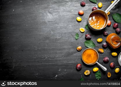 Fresh puree of ripe plums with green leaves. On a black chalkboard.. Fresh puree of ripe plums with green leaves.