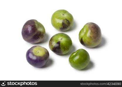 Fresh purple and green tomatillos on white background