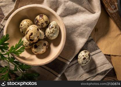 Fresh quail eggs on a ceramic bowl, brown wooden table. Raw quail eggs close-up on a culinary background. Concept of preparation for cooking