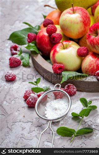 Fresh raspberries and apples on old wooden plate on a concrete background. Healthy concept. Natural healthy food. Organic food.
