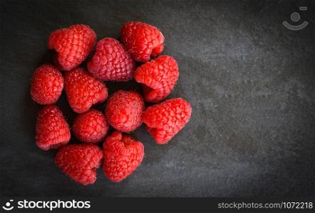Fresh raspberries fruit on dark background top view
