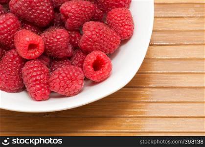 Fresh raspberries in a round white plate