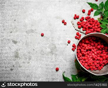 Fresh raspberries in the old pot. On a stone background.. Fresh raspberries in the old pot.