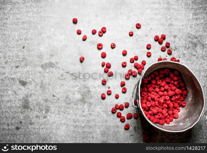 Fresh raspberries in the old pot. On a stone background.. Fresh raspberries in the old pot.