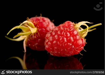 Fresh raspberries on black reflective background.