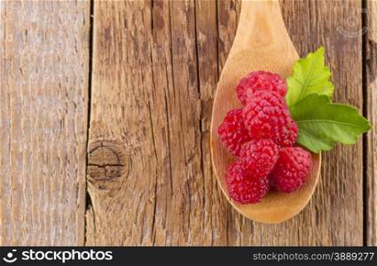 fresh raspberry in wooden spoon on wooden table