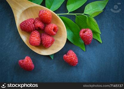 Fresh raspberry on wooden spoon / Top view red ripe raspberries fruit and green leaf on dark background