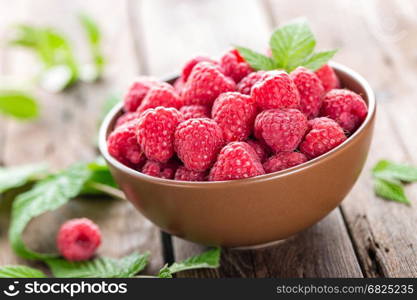 Fresh raspberry with leaves on wooden background