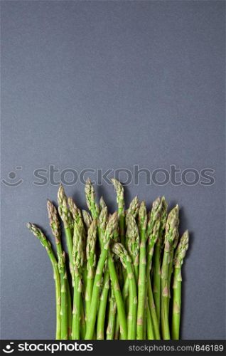 Fresh raw asparagus for cooking vegetarian food on a gray background with copy space. Top view. Vegan healthy nutrition concept.. Heap of fresh natural asparagus on a gray background.