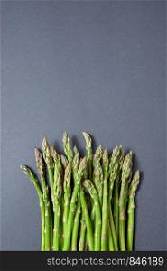 Fresh raw asparagus for cooking vegetarian food on a gray background with copy space. Top view. Vegan healthy nutrition concept.. Heap of fresh natural asparagus on a gray background.