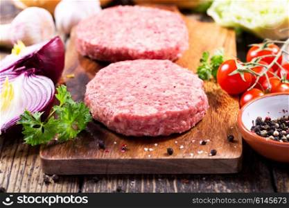 Fresh raw beef burger for hamburger with vegetables on wooden board
