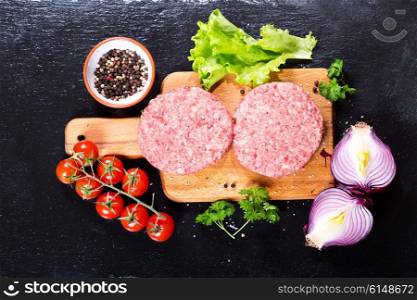 Fresh raw beef burger for hamburger with vegetables on wooden board, top view