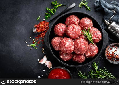 Fresh raw beef meatballs with spices and tomato sauce