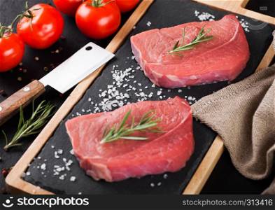 Fresh raw beef steak meat on stone kitchen board with hatchet and fresh tomatoes