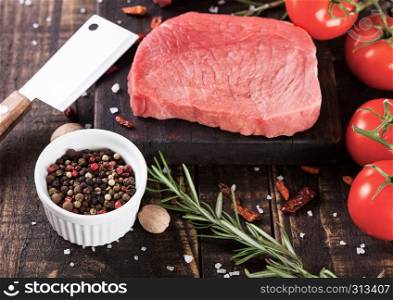 Fresh raw beef steak meat on wooden kitchen board with hatchet and pepper