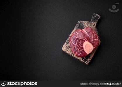 Fresh raw beef steak with bone or ossobuco with salt, spices and herbs on dark concrete background