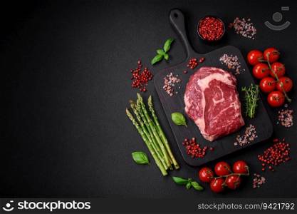 Fresh, raw beef steak with salt, spices and herbs on a dark textured background