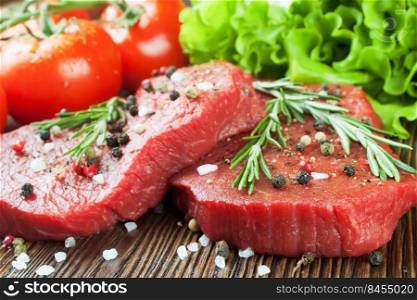 Fresh raw beef steak with spice and vegetable on brown wooden table. Fresh raw meat beef steak