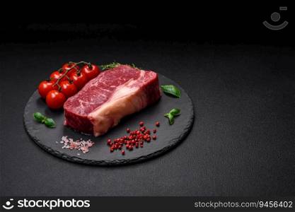 Fresh raw beef striploin steak with salt, spices and herbs on a dark concrete background
