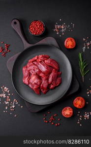 Fresh raw beef with salt, spices and herbs on a dark concrete background