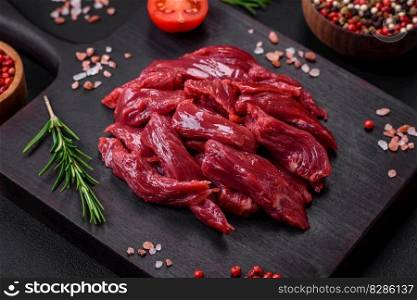 Fresh raw beef with salt, spices and herbs on a dark concrete background