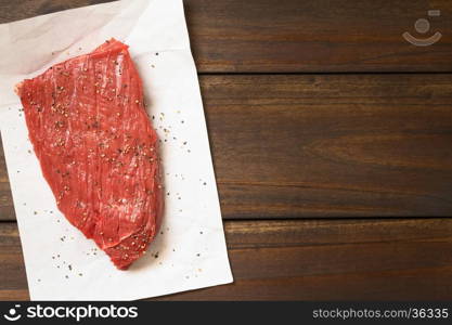 Fresh raw boneless beef meat with ground black pepper, photographed overhead with natural light (Selective Focus, Focus on the top of the slice)
