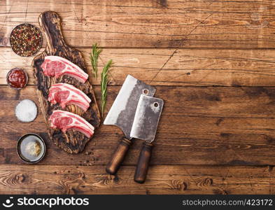 Fresh raw butchers lamb beef cutlets on chopping board with vintage meat hatchets on wooden background.Salt, pepper and oil