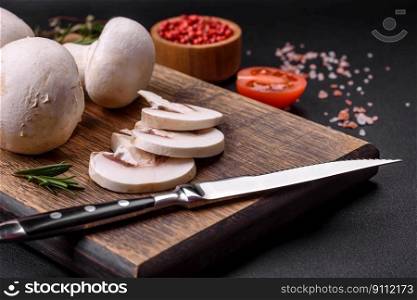Fresh raw ch&ignon mushrooms on a wooden cutting board with spices and herbs on a dark concrete background