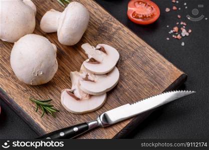Fresh raw ch&ignon mushrooms on a wooden cutting board with spices and herbs on a dark concrete background