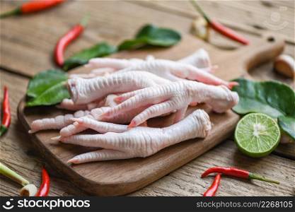 Fresh raw chicken feet for cooked food soup on the dark table kitchen background, Chicken feet on wooden cutting board with herbs and spices lemon chili garlic kaffir lime leaves