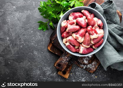 Fresh raw chicken hearts on dark background