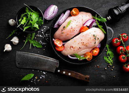 Fresh raw chicken meat, fillet marinated with spices, onion and tomatoes on black background. Top view