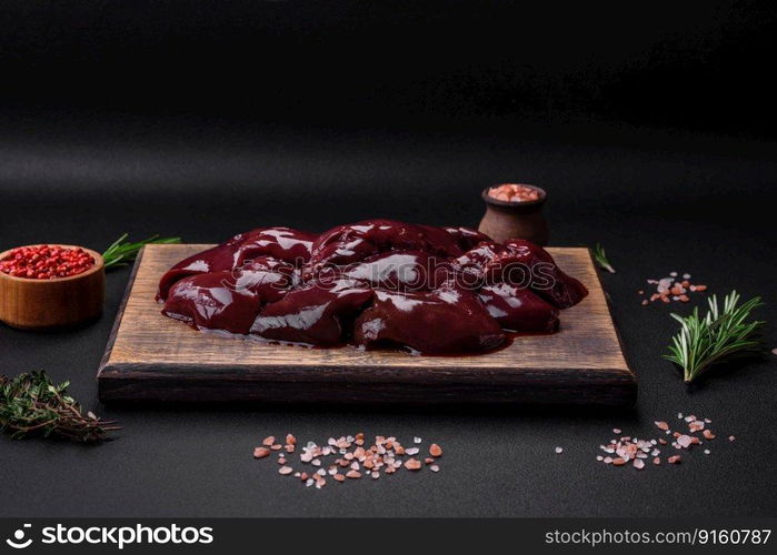 Fresh raw chicken, turkey or duck liver with salt, spices and herbs on a dark concrete background