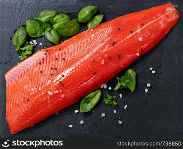 Fresh raw copper river sockeye salmon fillet on natural stone with herbs and seasoning