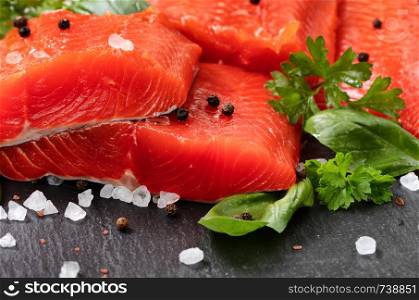 Fresh raw copper river sockeye salmon fillets on natural stone with herbs and seasoning