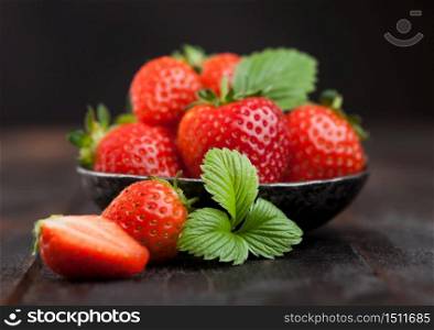 Fresh raw farm organic strawberries with leaf in steel bowl on wooden background.