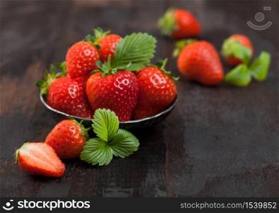 Fresh raw farm organic strawberries with leaf in steel bowl on wooden background. Top view