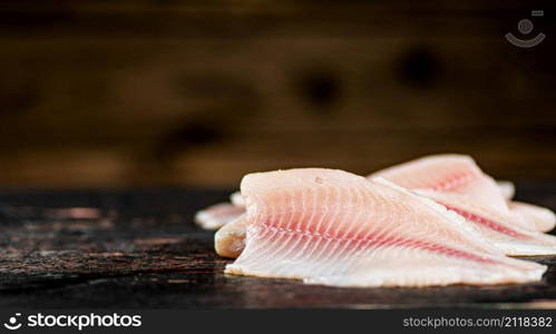 Fresh raw fish fillet on the table. Against a dark background. High quality photo. Fresh raw fish fillet on the table.