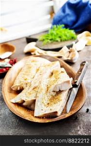 Fresh raw fish fillet with spices, pepper, salt, basil on a stone plate, top view, square