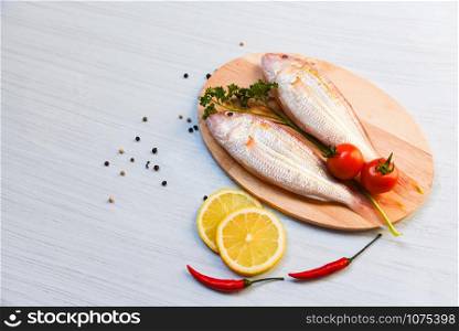 Fresh raw fish on cutting board with tomato lemon chilli and green parsley in the seafood restaurant