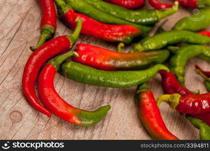 Fresh raw green and red peppers on wooden background
