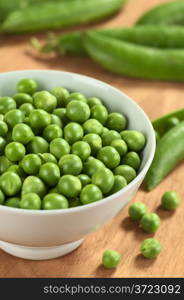 Fresh raw green pea (lat. Pisum Sativum) in white bowl (Selective Focus, Focus on the peas in the middle of the bowl). Fresh Raw Green Pea in White Bowl