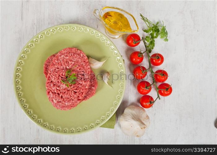 Fresh raw hamburger meat with parsley served on a green plate
